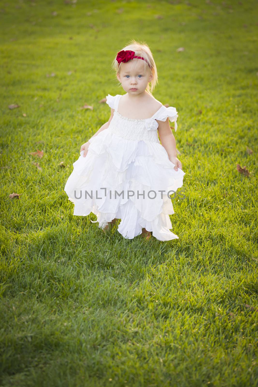 Beautiful Adorable Little Girl Wearing White Dress In A Grass Field.