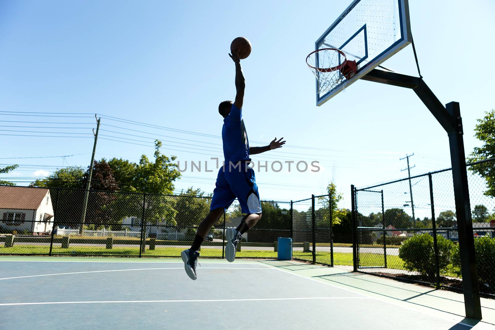 Young basketball player driving to the hoop for a high flying slam dunk.