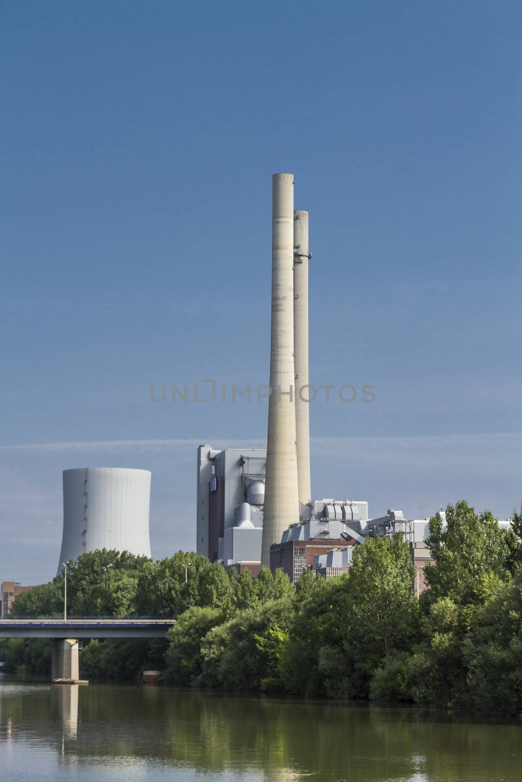 german coal-fired power station at the river Neckar with blue sky and bridge.
