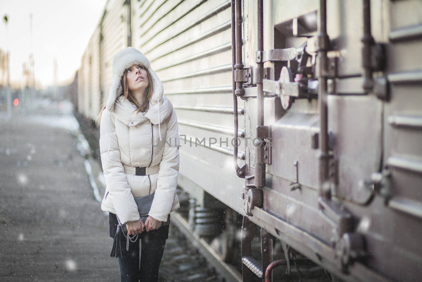 Young woman in fur hat and down jacket on a railroad station
