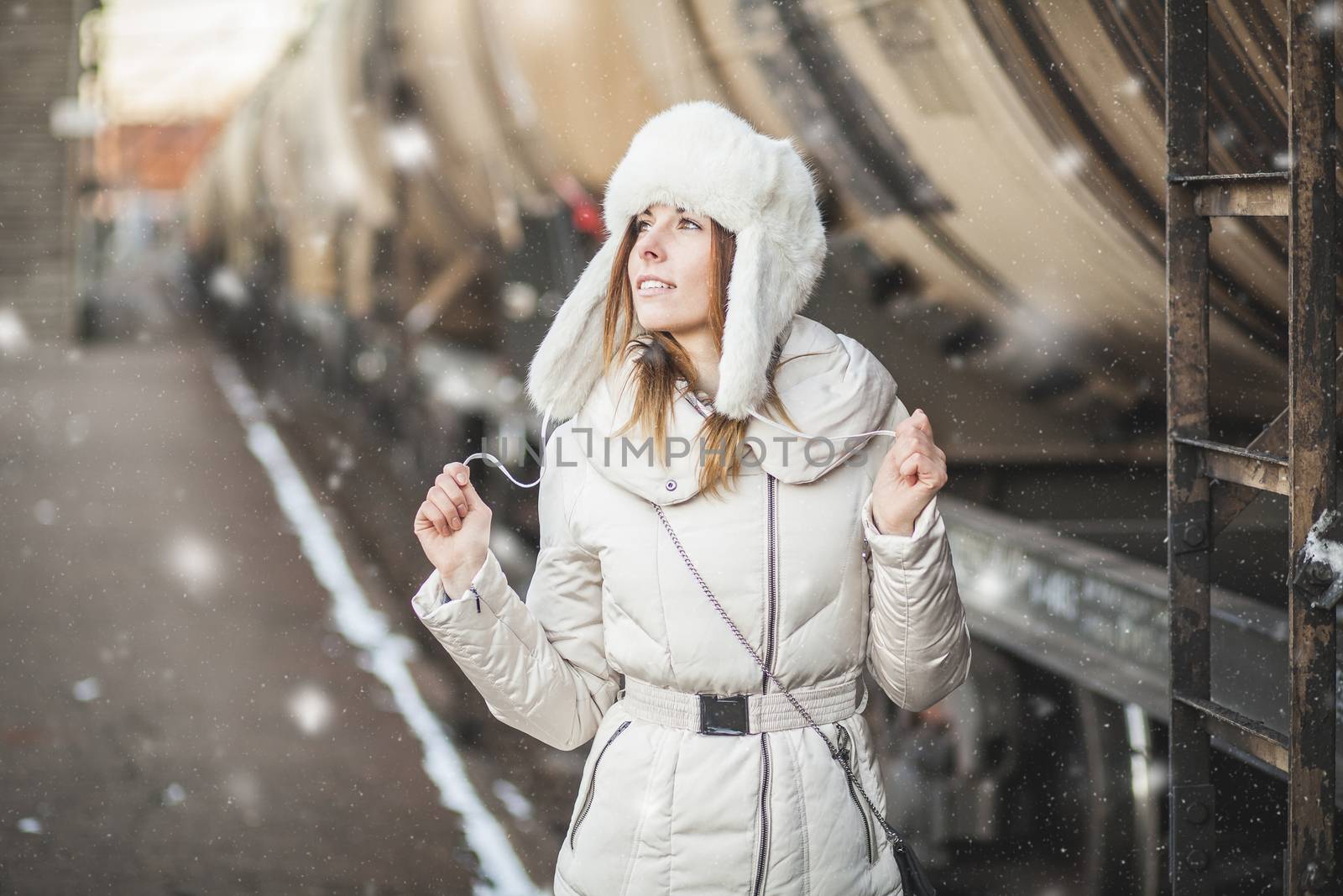 Young woman in fur hat and down jacket near the cargo carriage