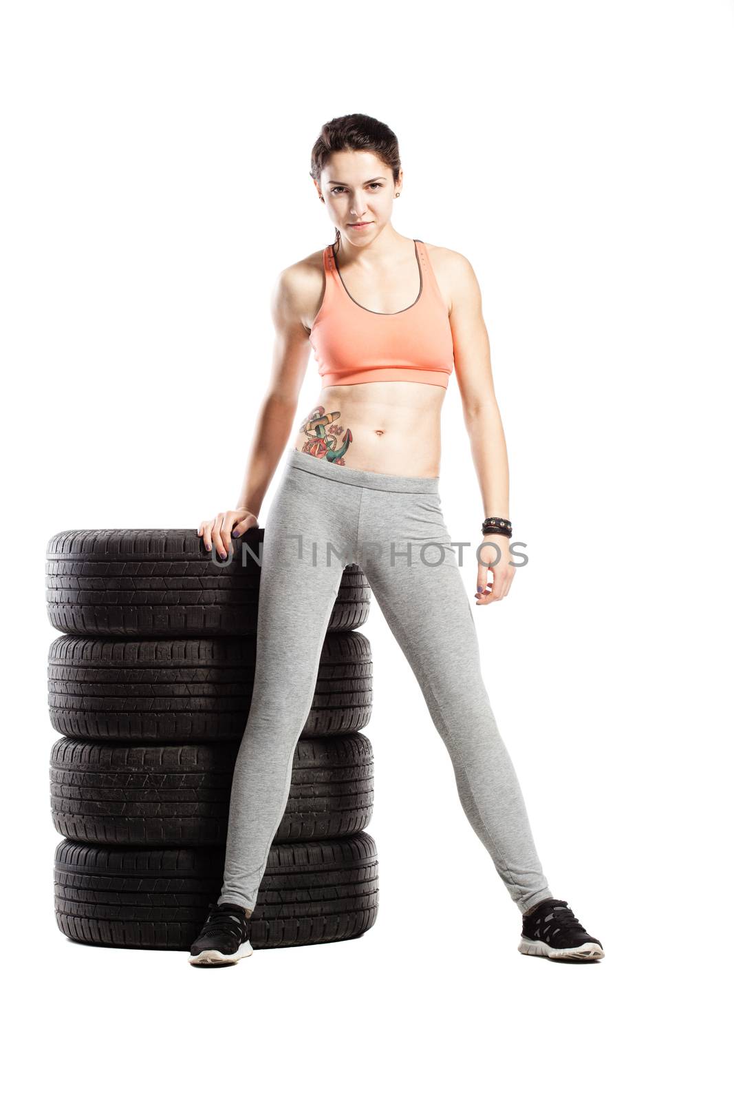 fitness girl with set of tyres, against white background