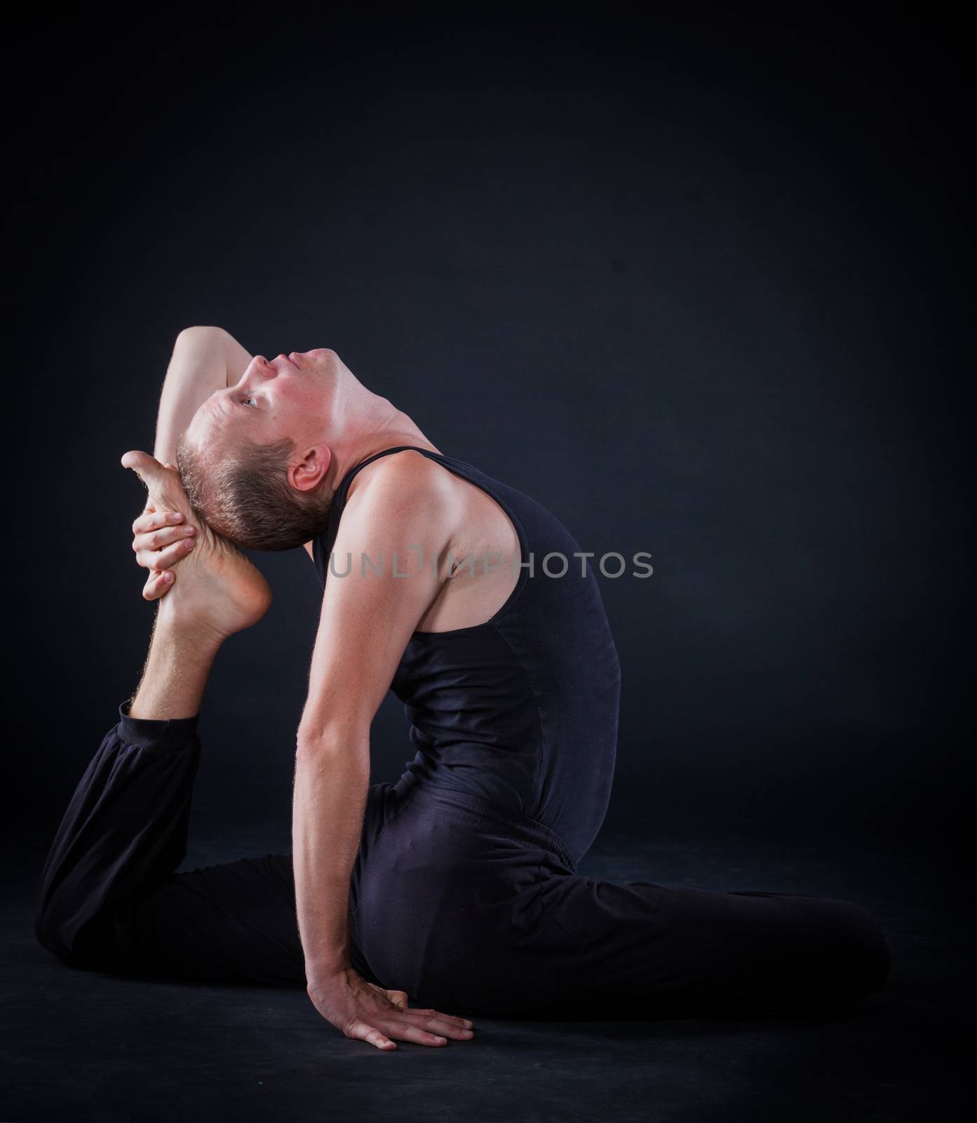 Handsome man doing yoga. Shot on black background