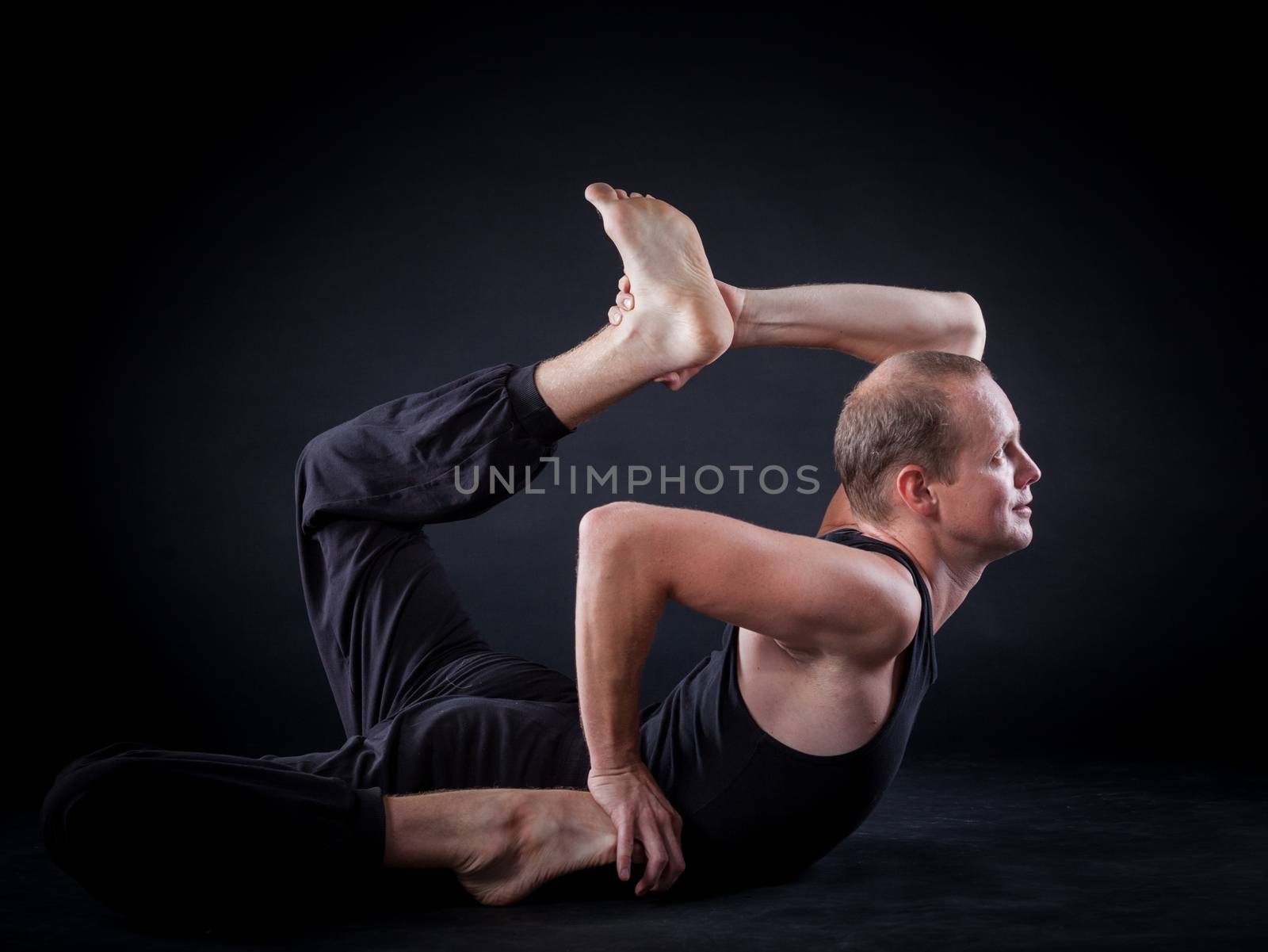 Handsome man doing yoga. Shot on black background