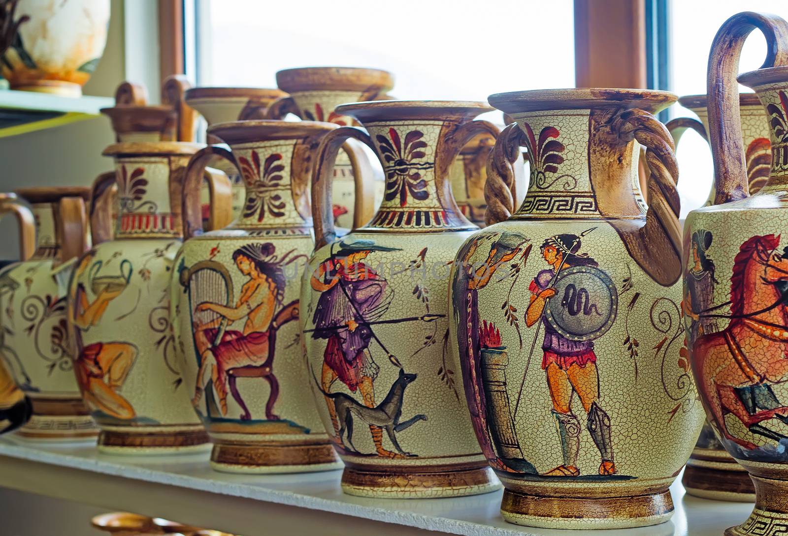 On the shelf in the store are beautiful ceramic vases with painted antique subjects.
