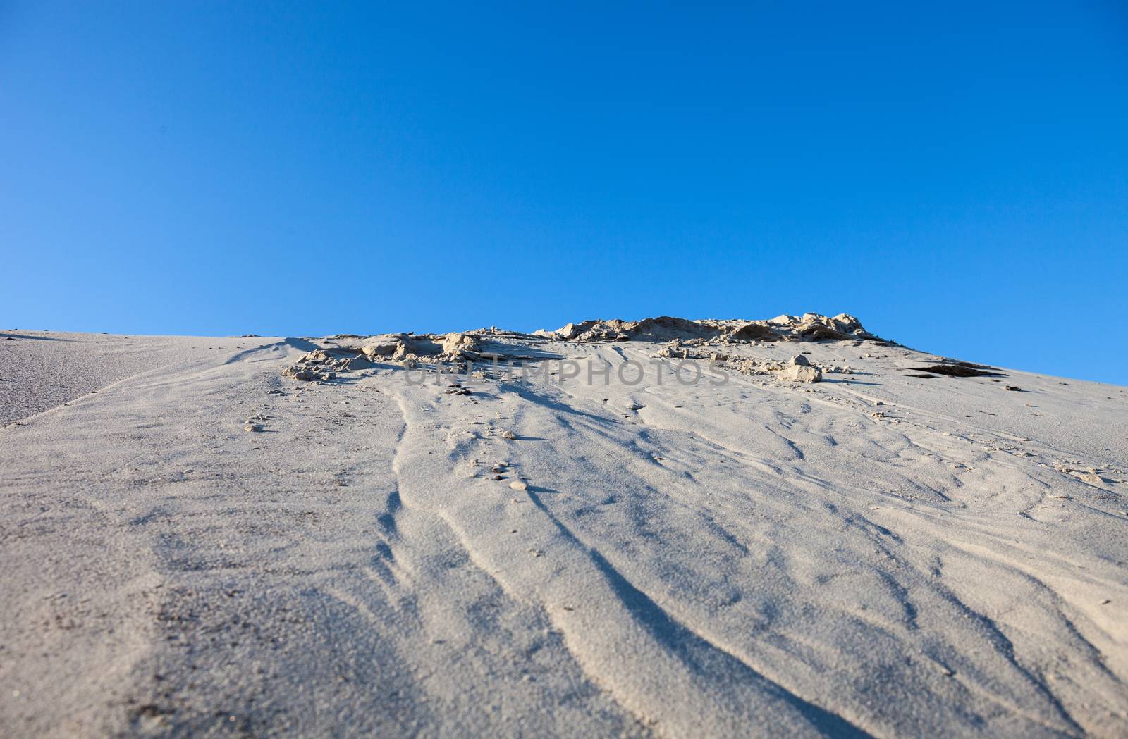 Gray sand dunes and the blue sky.