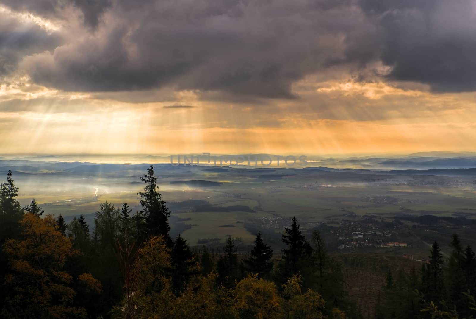 Godly light rays passing through clouds in the early morning above hilly countryside