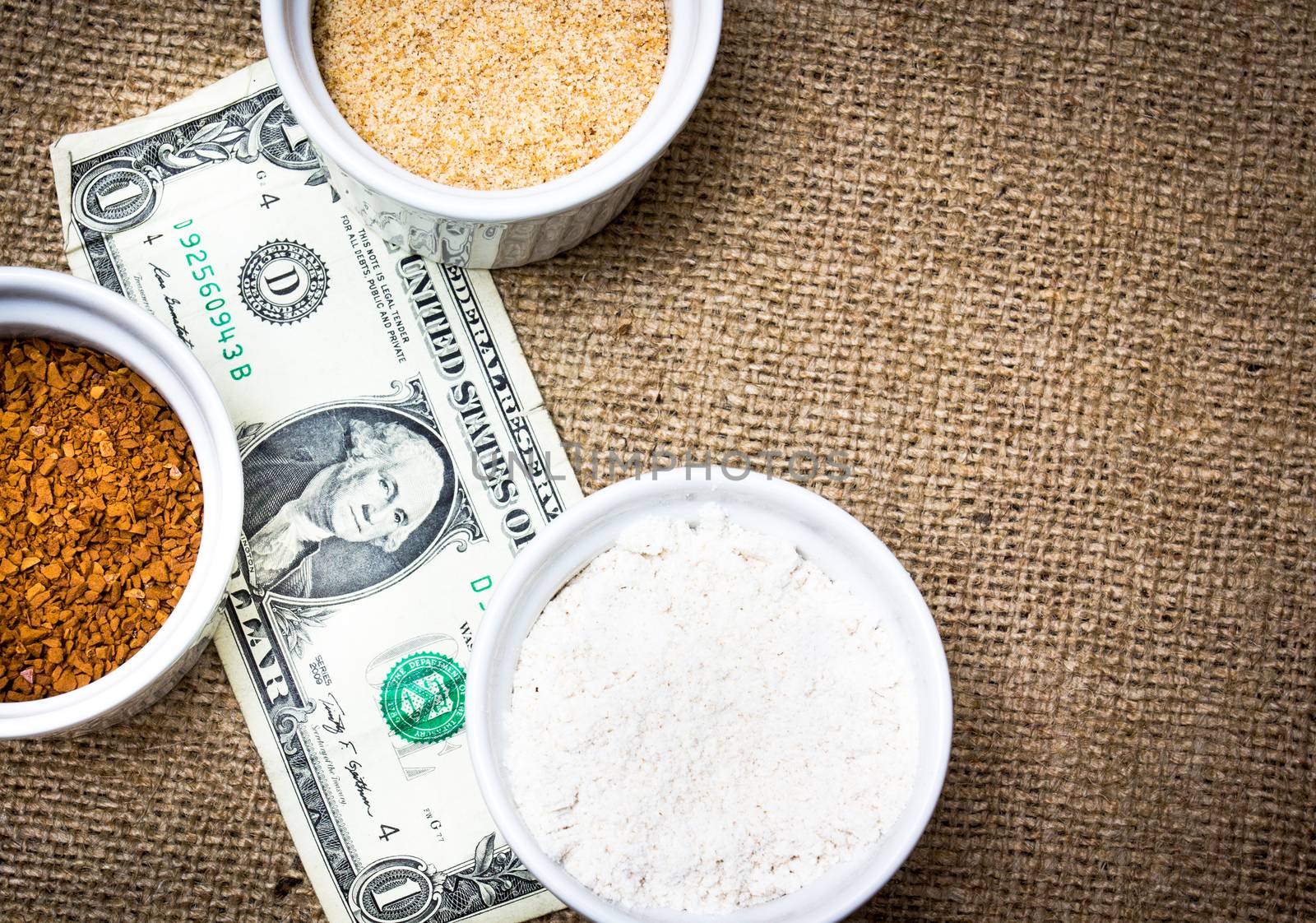 Various type of ingredients poured in several porcelain cups together with a dollar bill