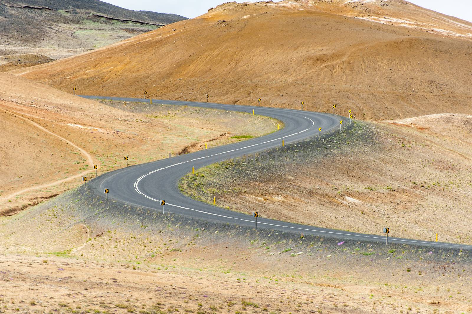 Road with cars leading through the mountain landscape looks like a big symmetric S letter, Iceland. 