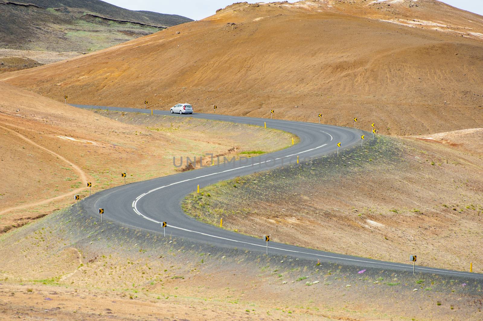 Road with cars leading through the mountain landscape looks like a big symmetric S letter, Iceland. 
