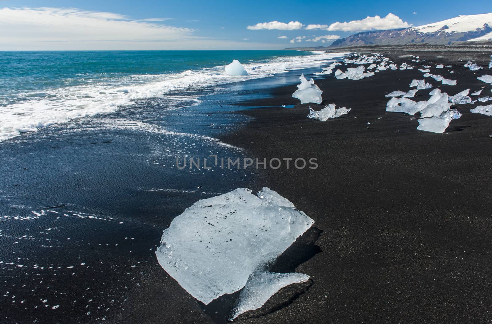 Beautiful beach in the South of Iceland with a black lava sand is full of icebergs from glaciers not far away