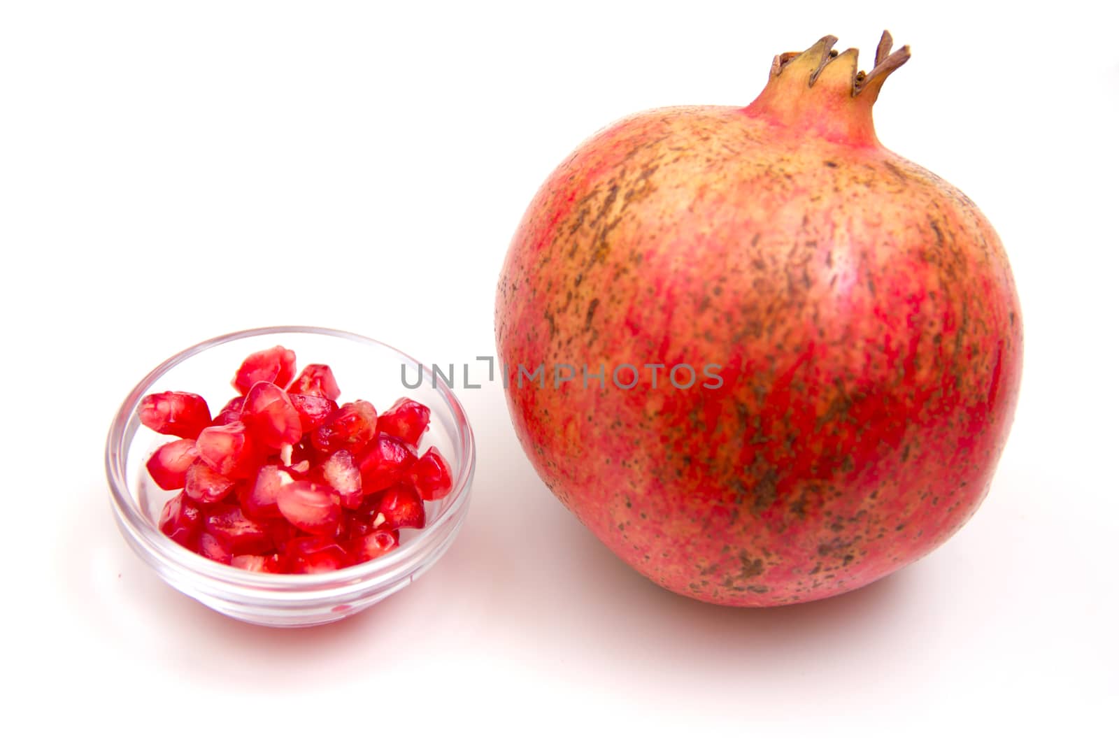 Pomegranate with grains seen up close on a white background