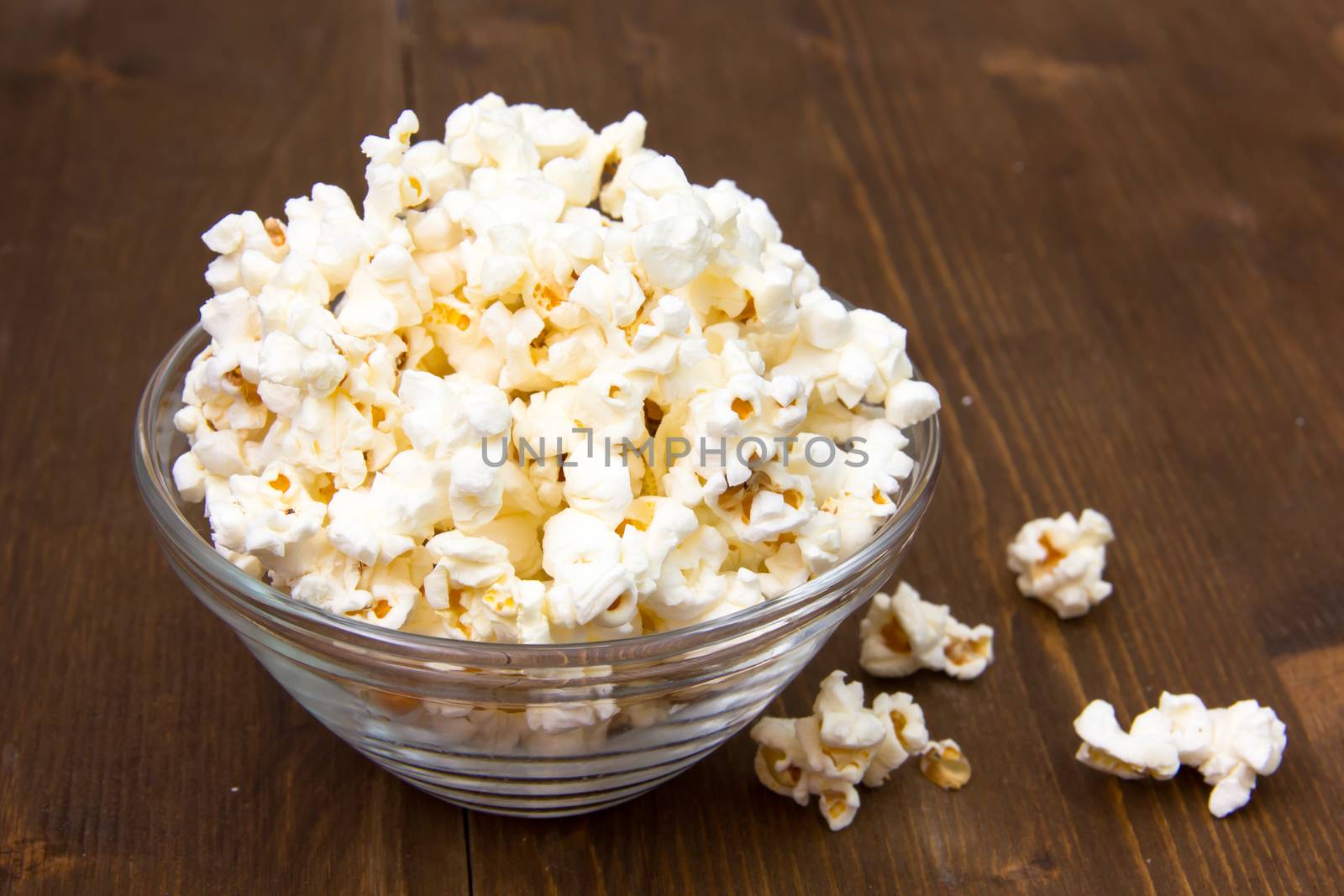 Popcorn in glass bowl on wooden table