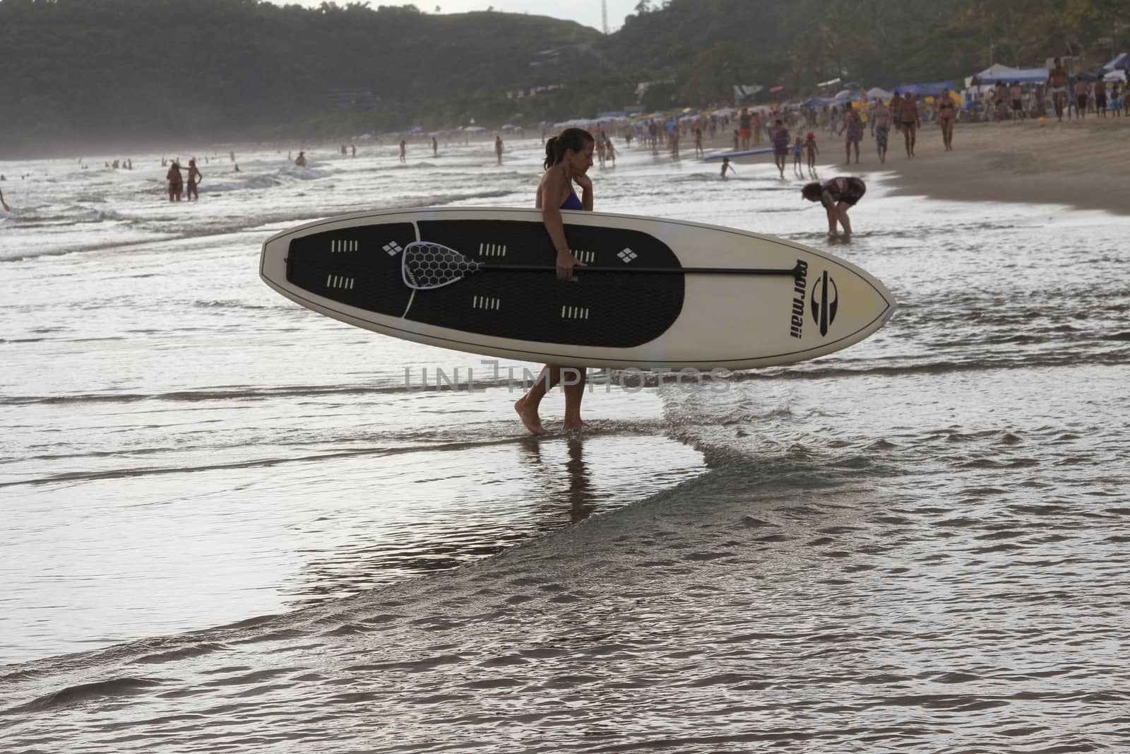 SAO SEBASTIAO, BRAZIL - JANUARY 04, 2015: An unidentified girl carring on a board of stand up paddle in the evening on a beach in Brazil.