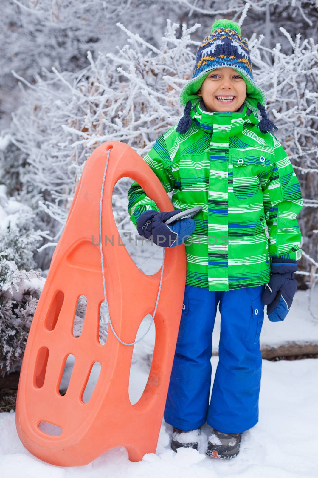 Little boy having fun with sled in winter park by maxoliki