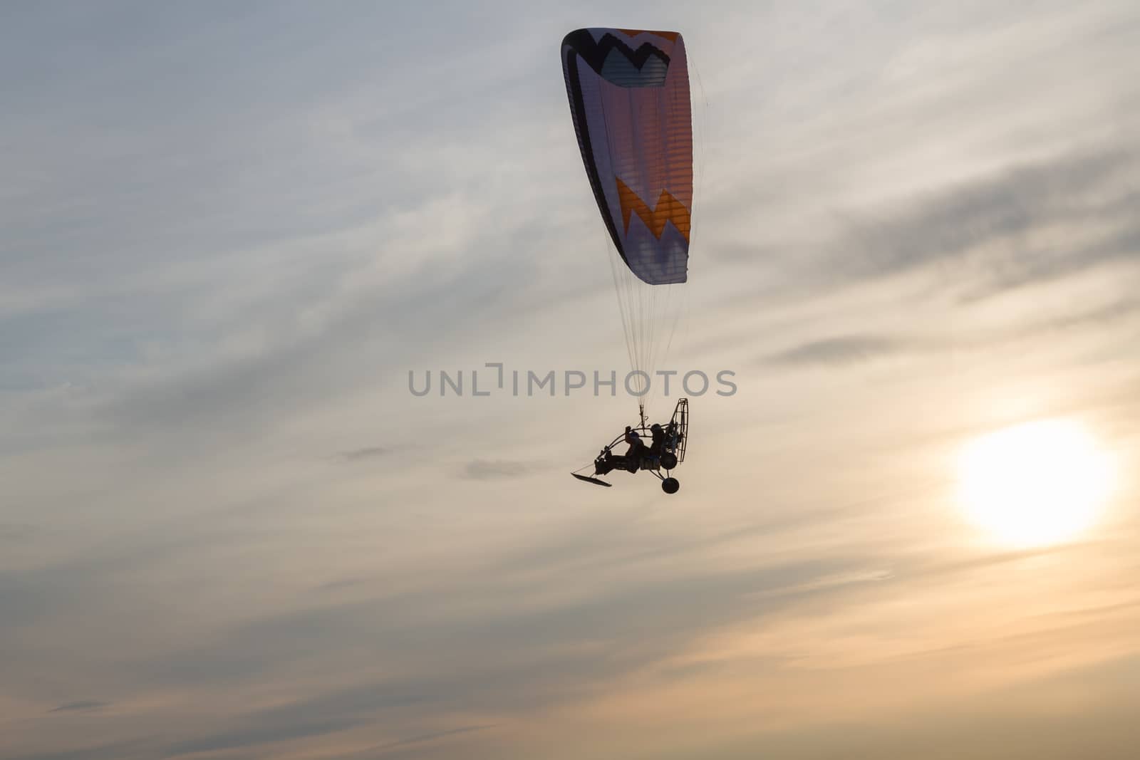 Powered paragliding flying against the backdrop of the setting sun