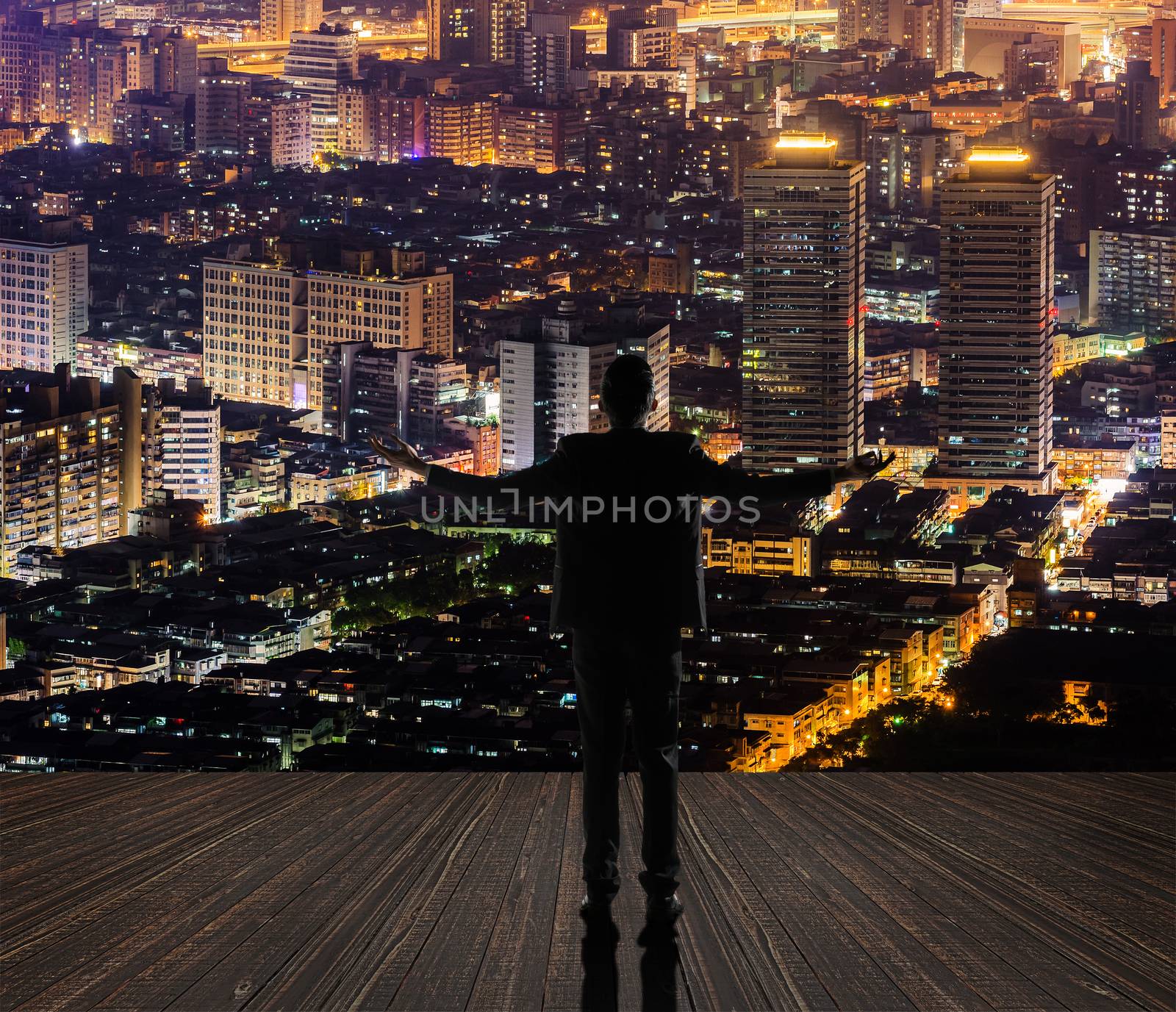 Silhouette of businessman open arms against city with copyspace.
