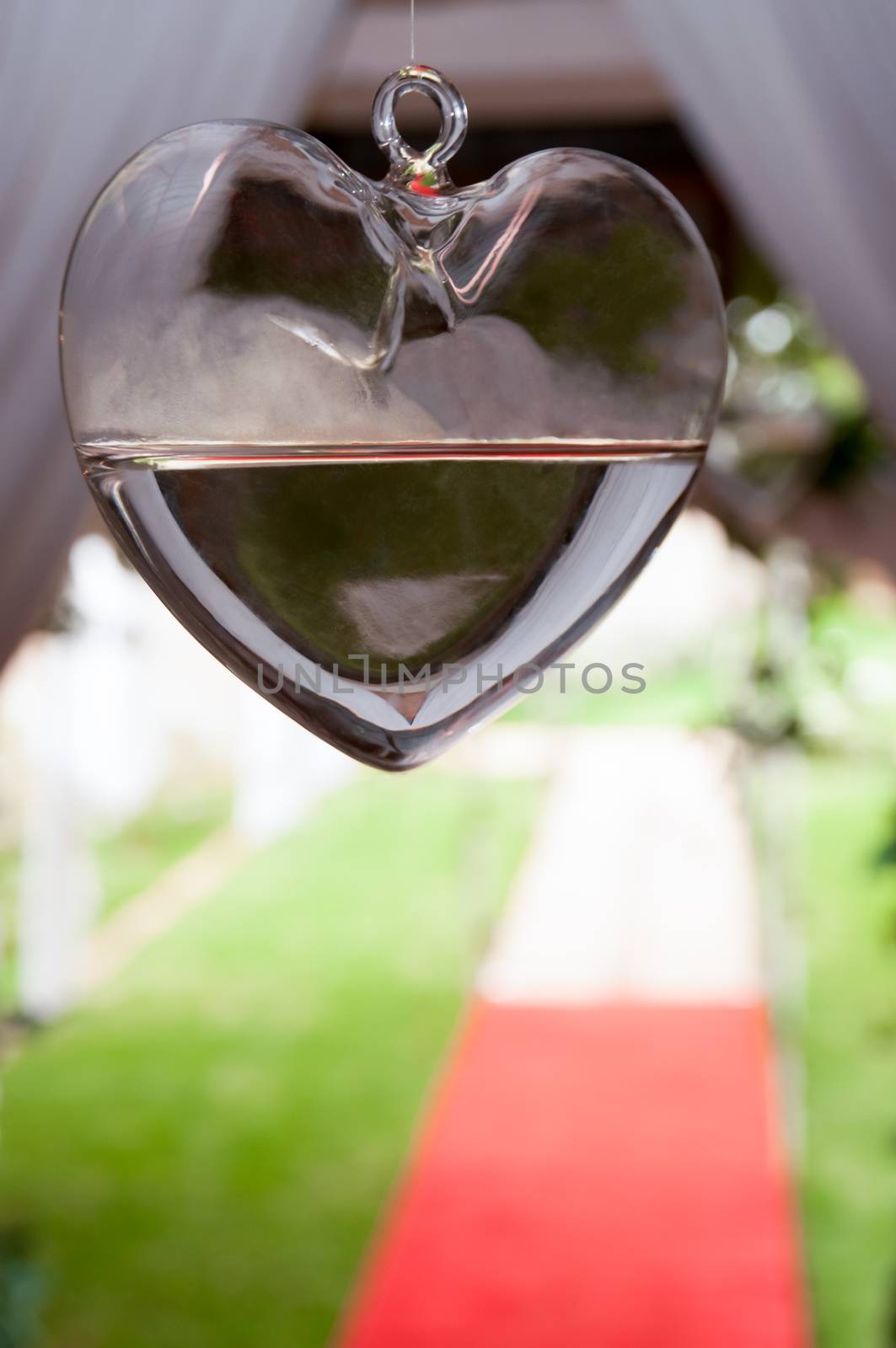 Heart of glass hanging from ceiling at entrance with red carpet.