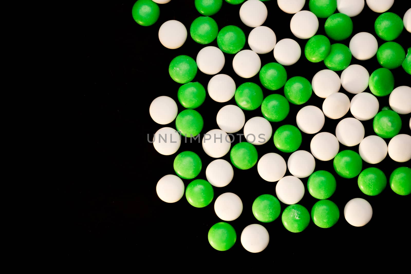 Green and white mints scattered on a black background.