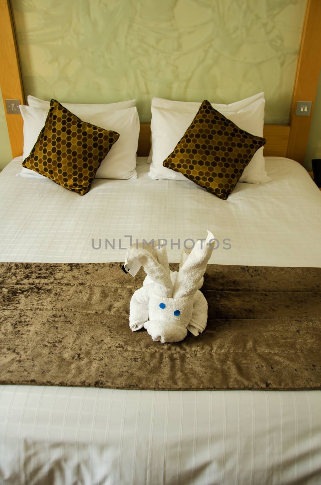 White brown bedroom with white plush toy on the brown bed cover.