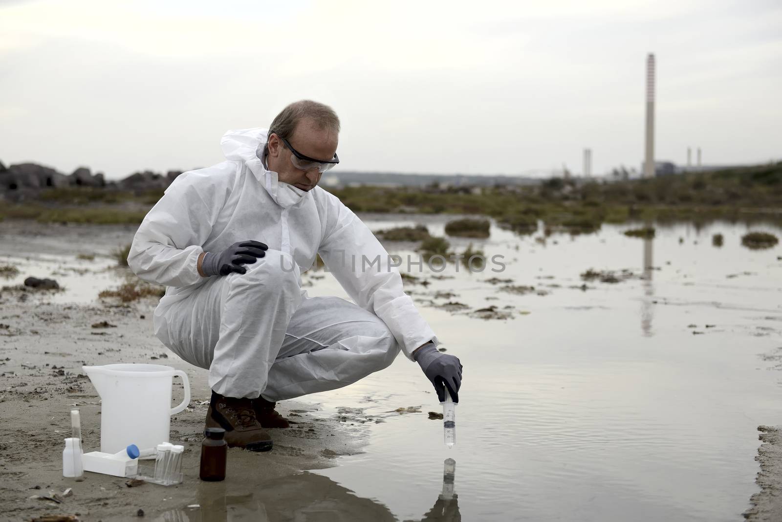 
Worker in a protective suit examining pollution in the water at the industry.
