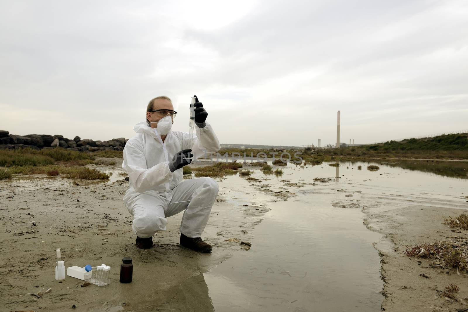 
Worker in a protective suit examining pollution in the water at the industry.
