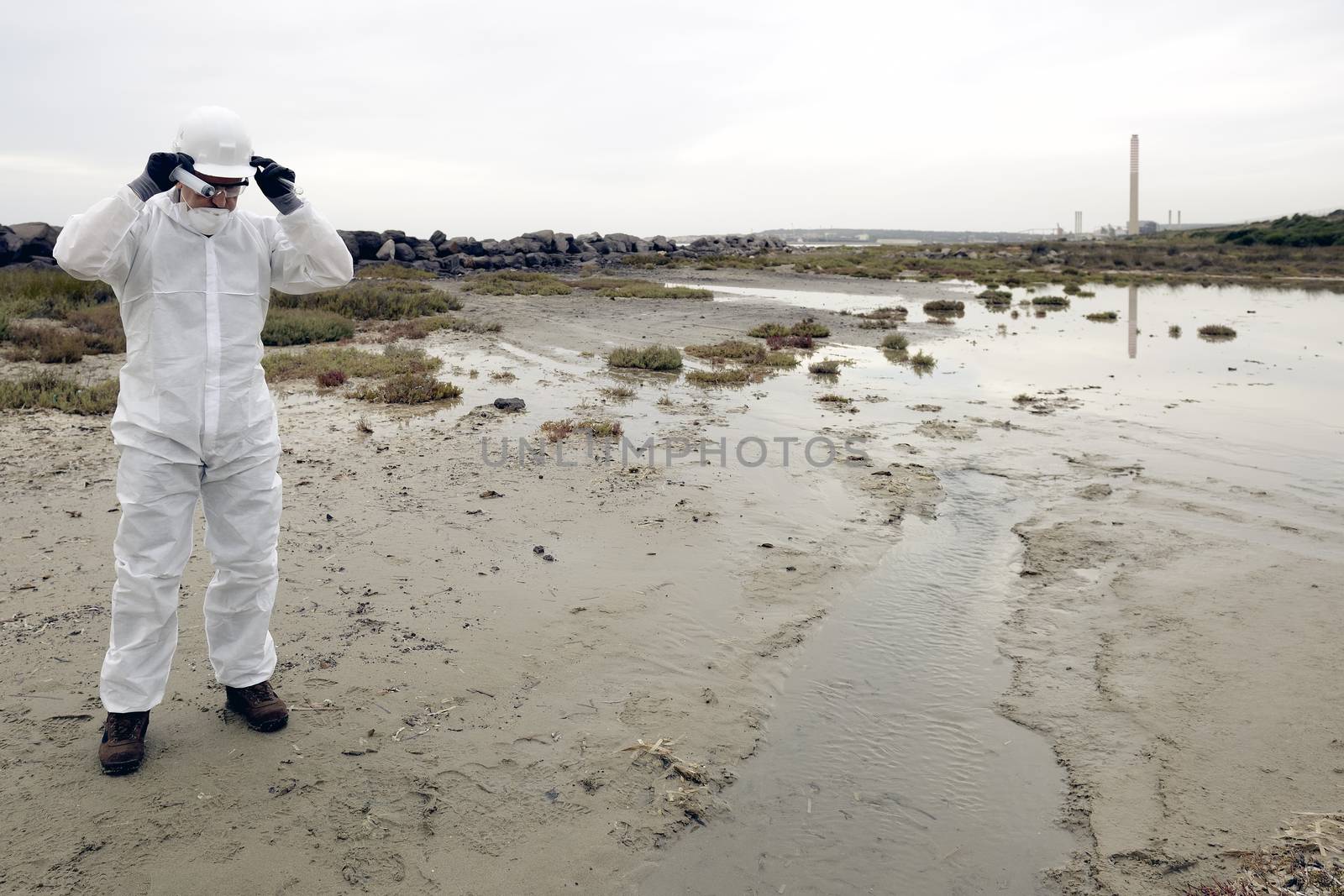 
Worker in a protective suit examining pollution in the water at the industry.