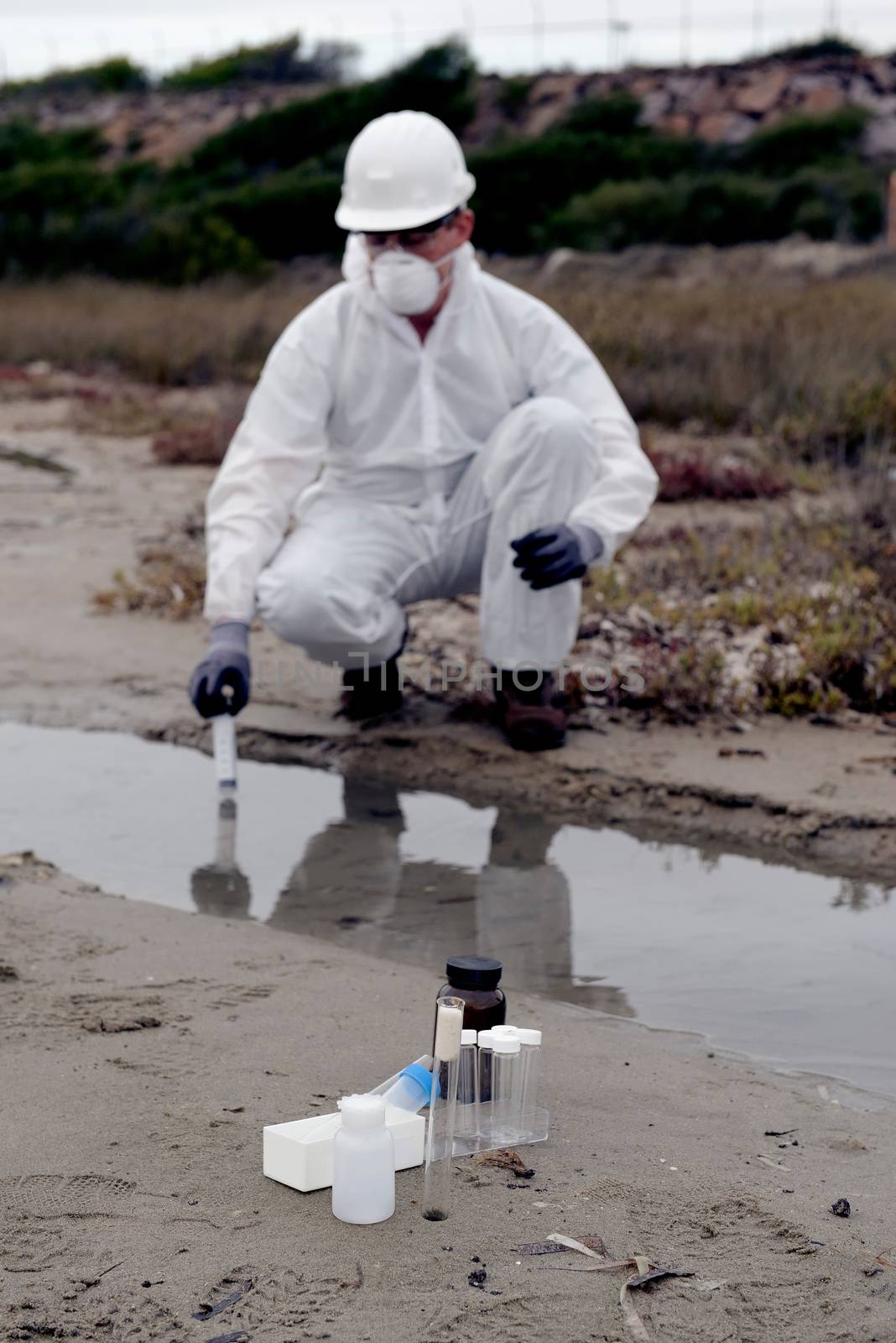 
Worker in a protective suit examining pollution in the water at the industry.