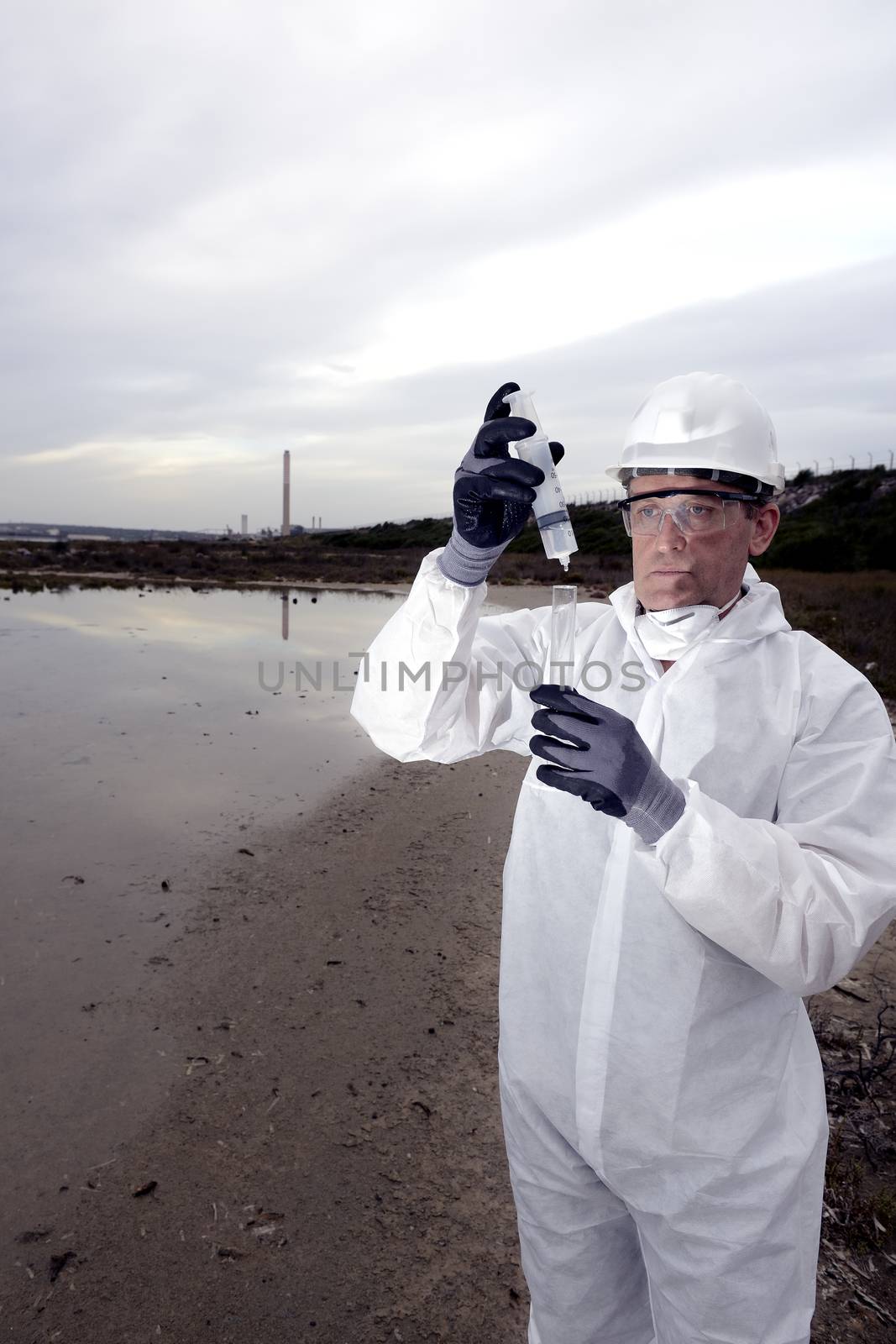 
Worker in a protective suit examining pollution in the water at the industry.