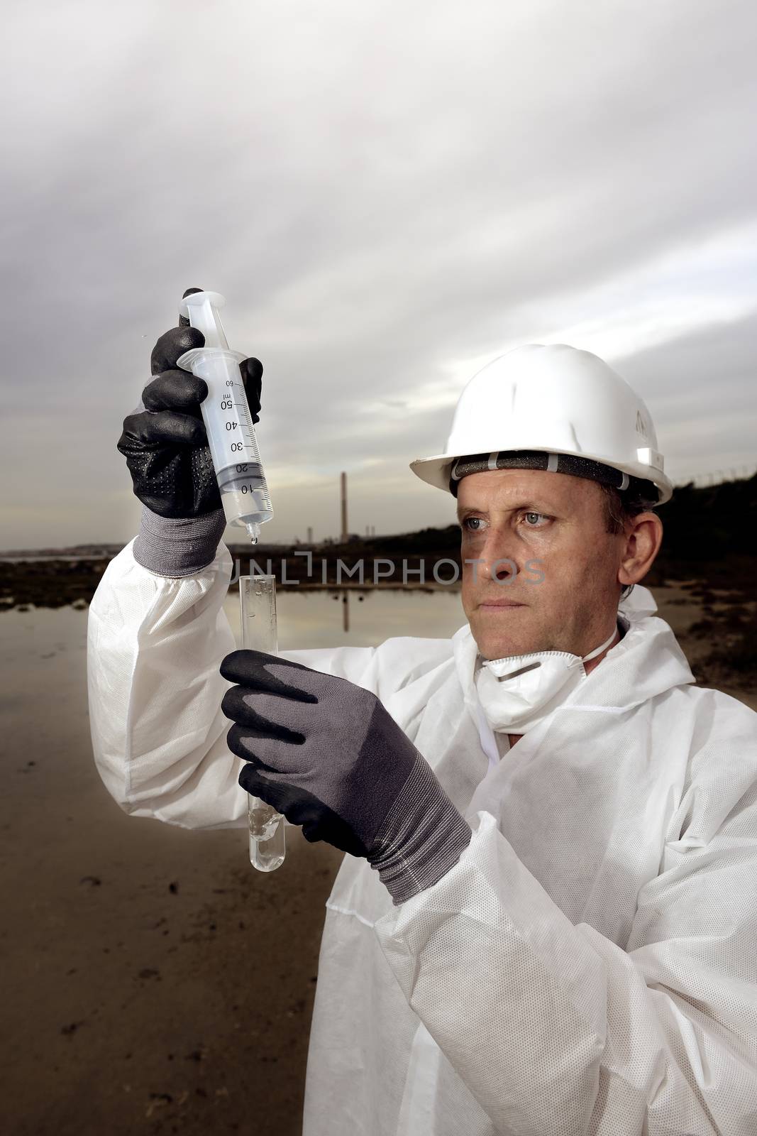 
Worker in a protective suit examining pollution in the water at the industry.