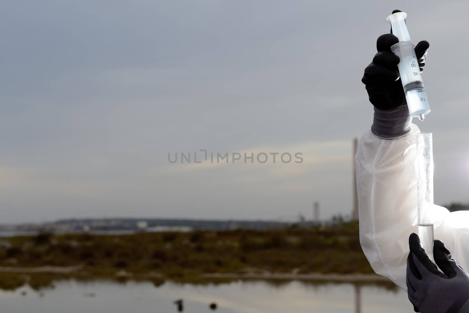 
Worker in a protective suit examining pollution in the water at the industry.