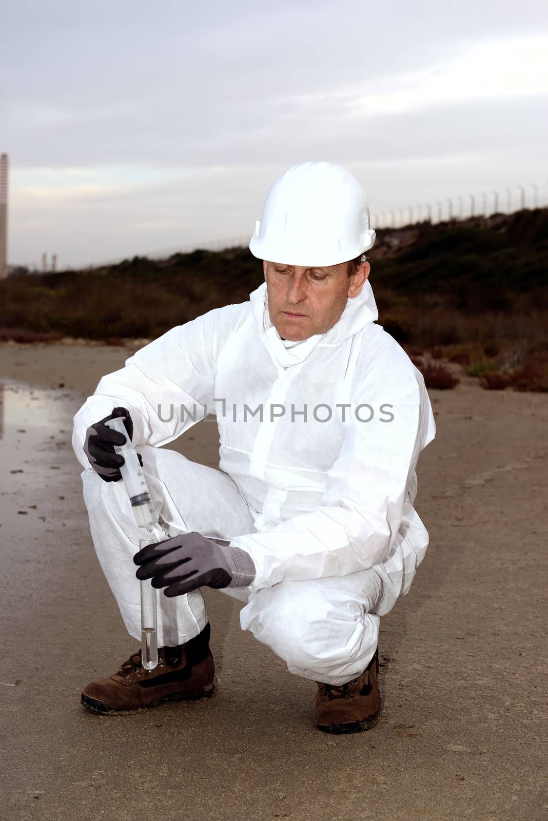 Worker in a protective suit examining pollution by osmar01