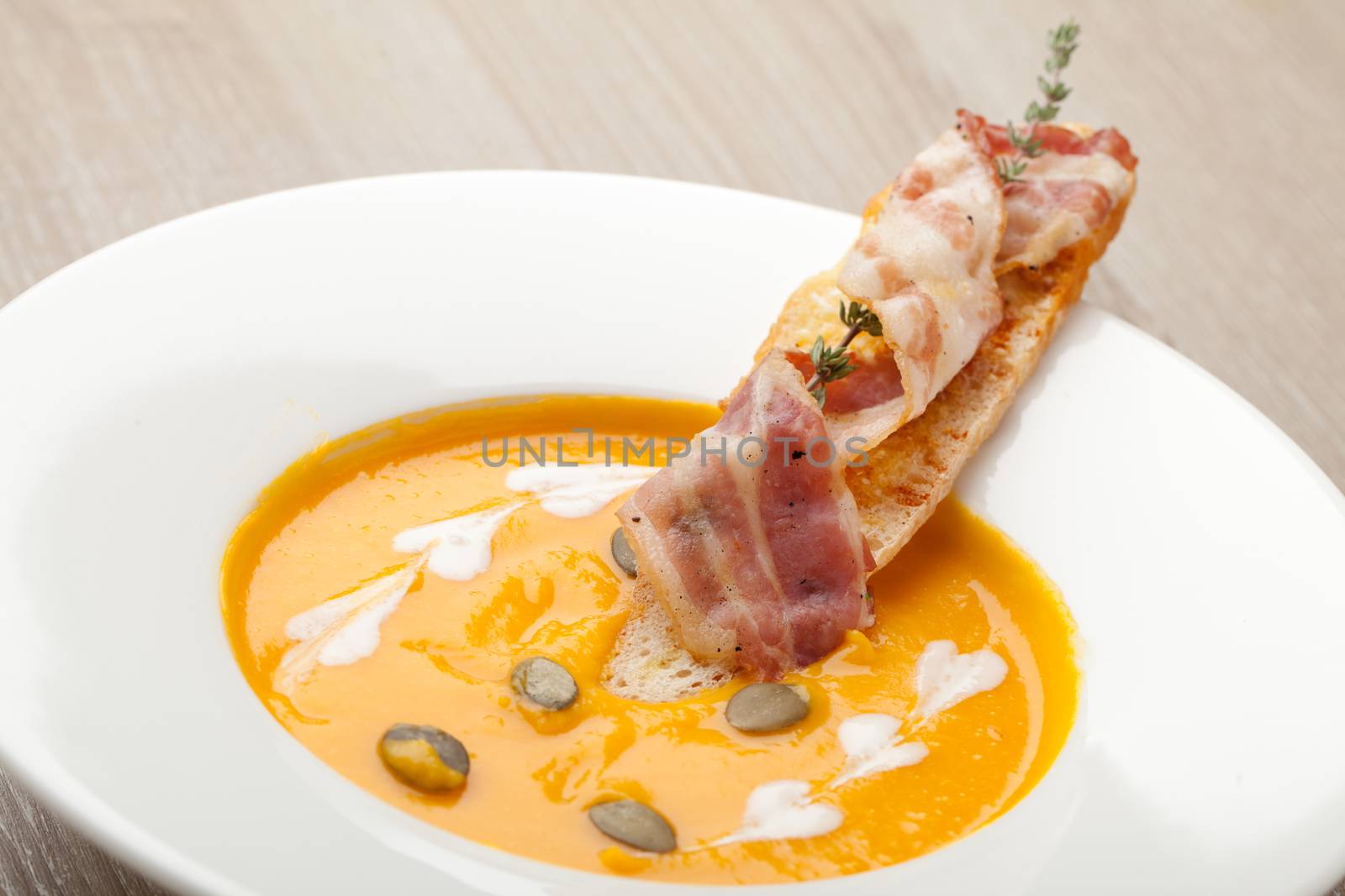 Pumpkin cream soup puree with bread slice, bacon and seeds by SergeyAK