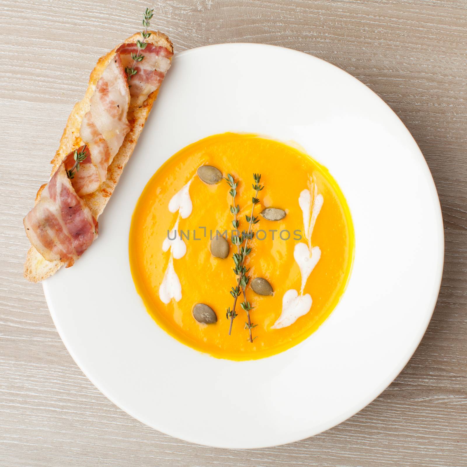 Pumpkin cream soup puree with bread slice, bacon and seeds by SergeyAK