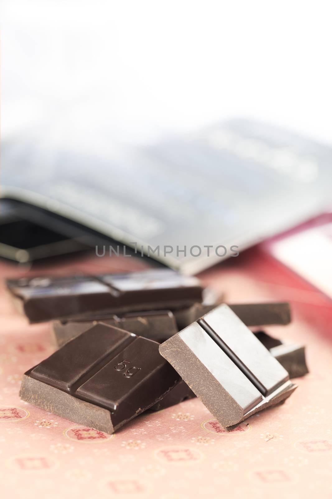 Broken pieces of dark chocolate for cooking, vertical orientation with copy space at top.