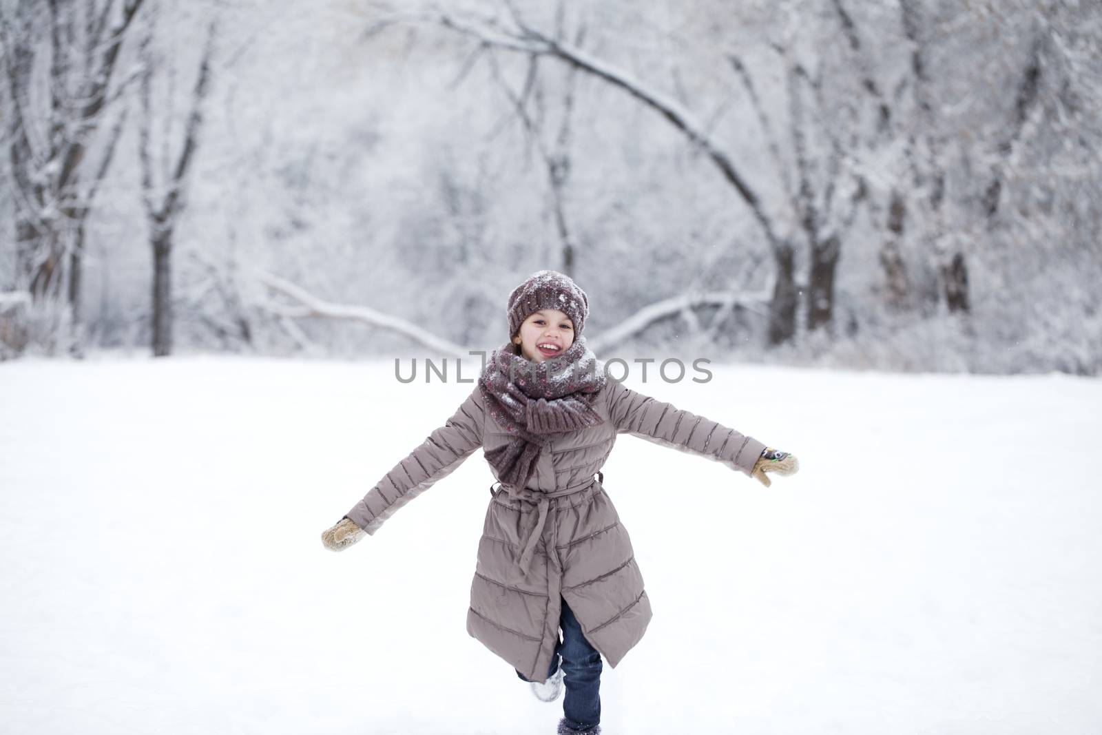 Happy little girl running on the background of snow covered wint by andersonrise