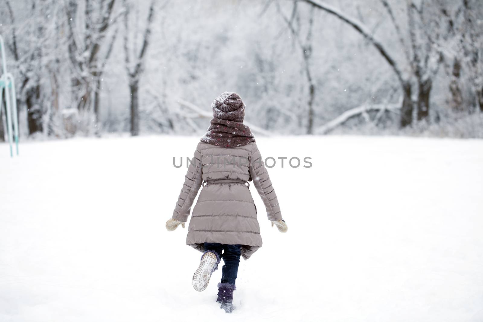 Happy little girl running on the background of snow covered wint by andersonrise