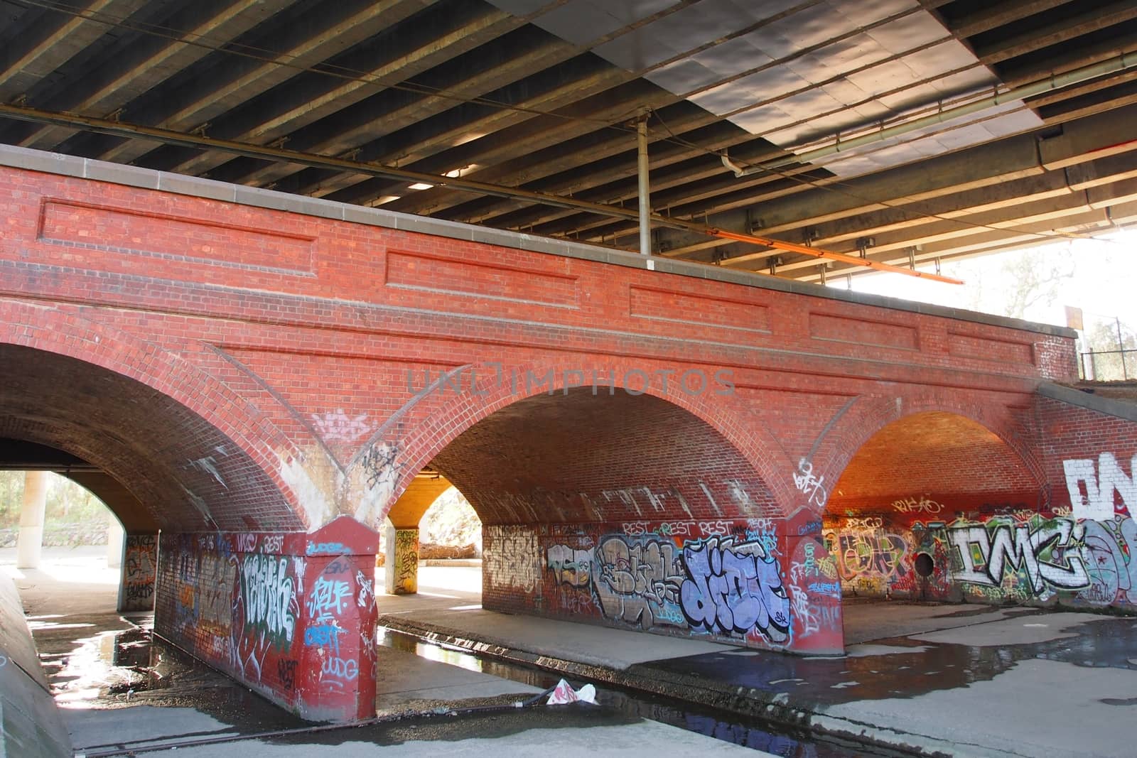 Under a storm drain bridge covered with graffitti