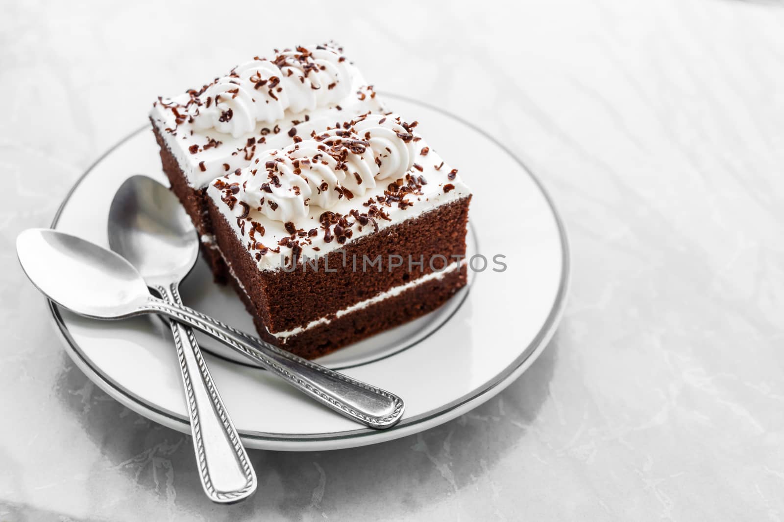 vintage style chocolate cakes with white cream on top and spoons on plate on marble table and blank area at right side