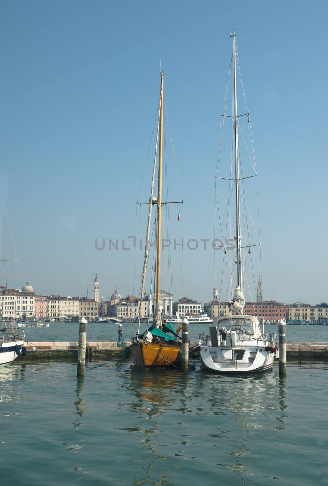 Two boats at the pier in Venice near the island of San Giorgio on a clear spring day