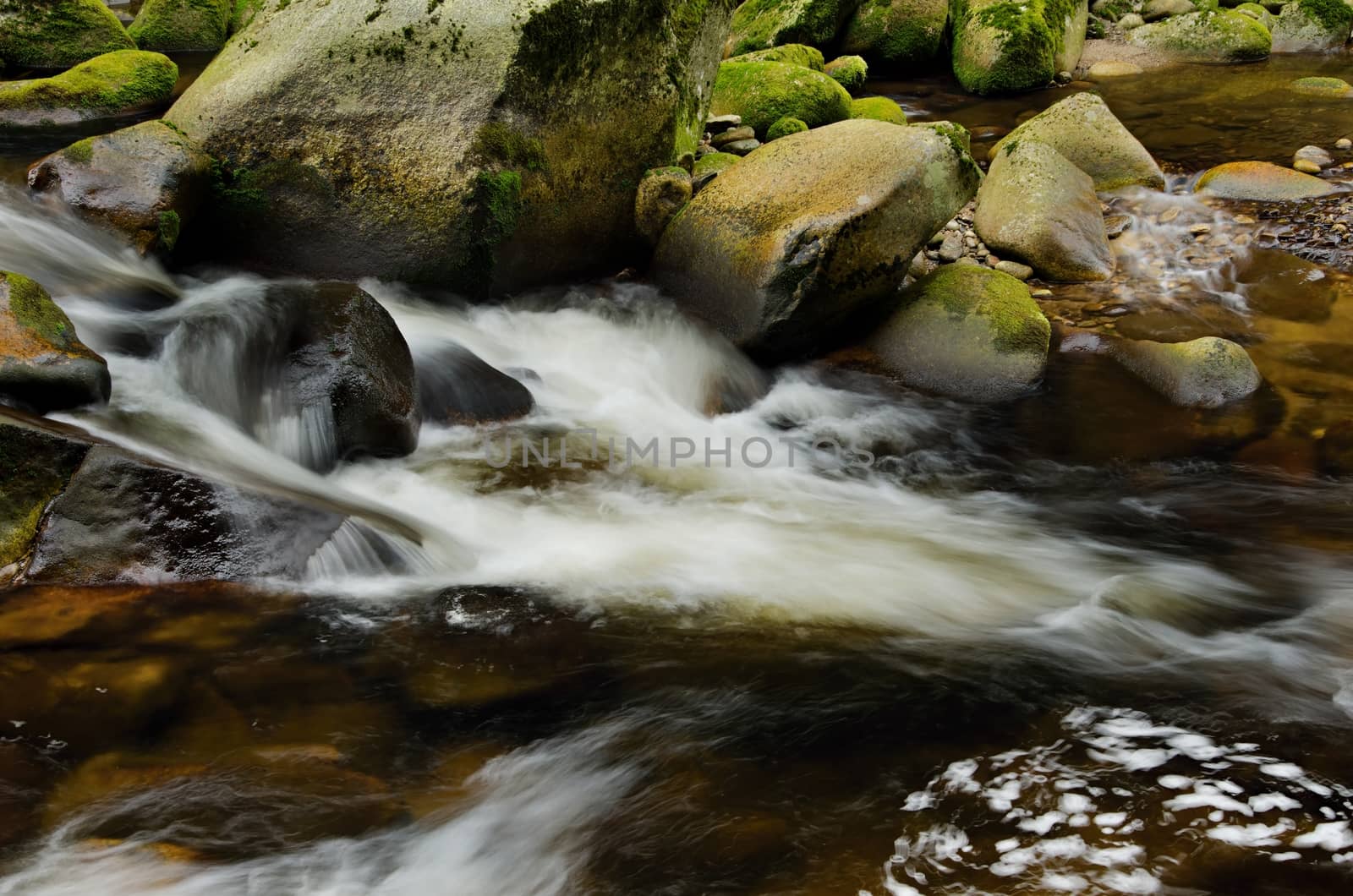 Detail of small beautiful cascade between mossy stones. 