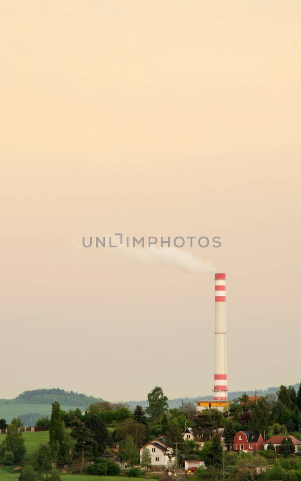 Town landscape in sunset with smoke stack.