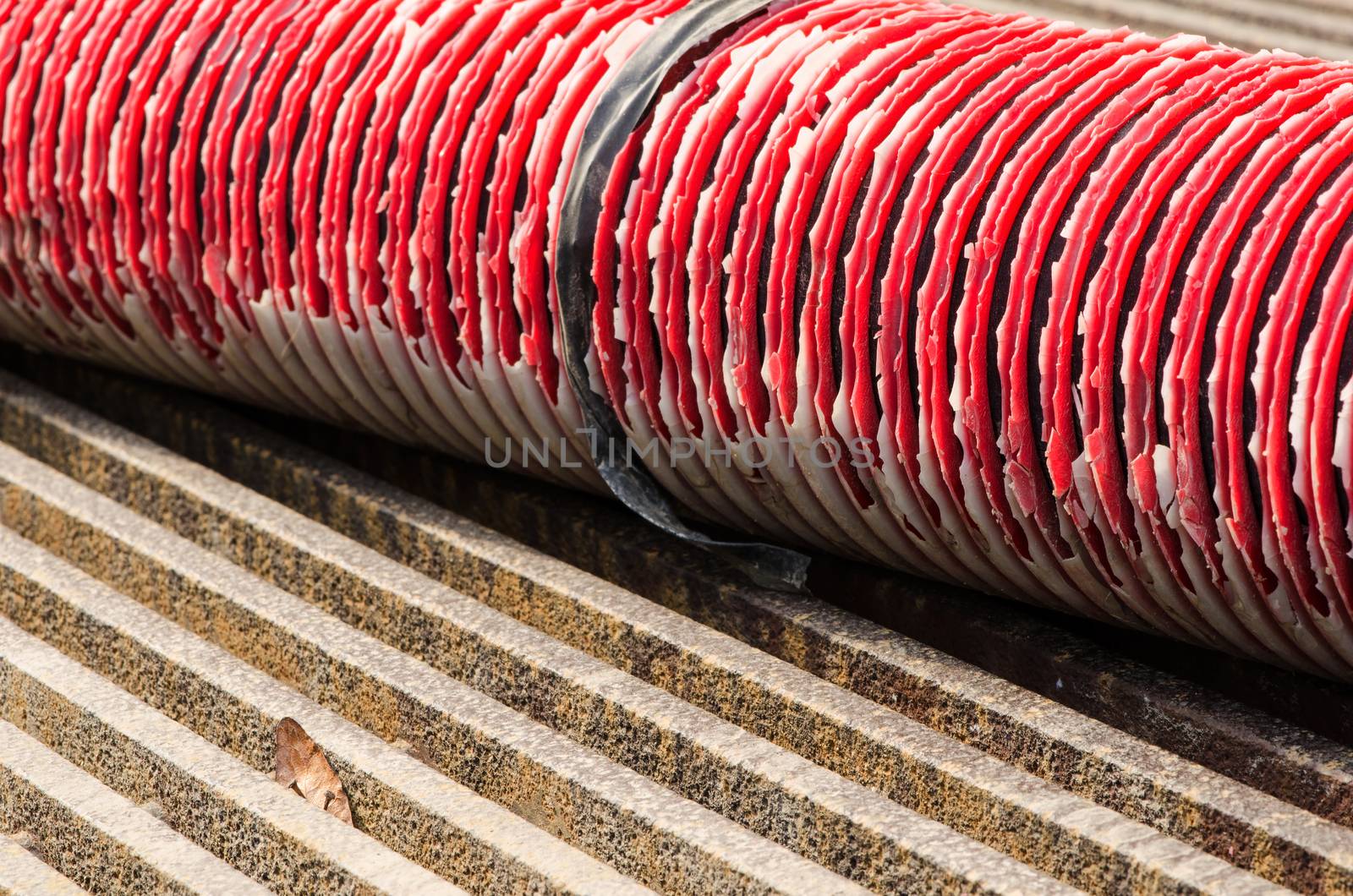 Old red pipe on the steel grate surface