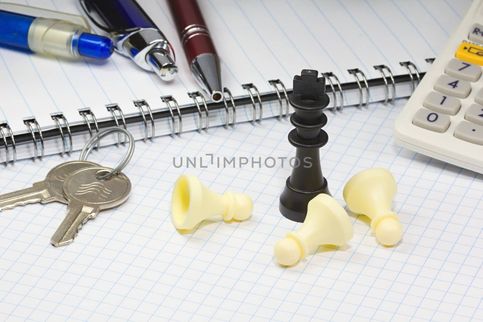 Photo shows keys, chess figurines, paper block and pencils on a business table.