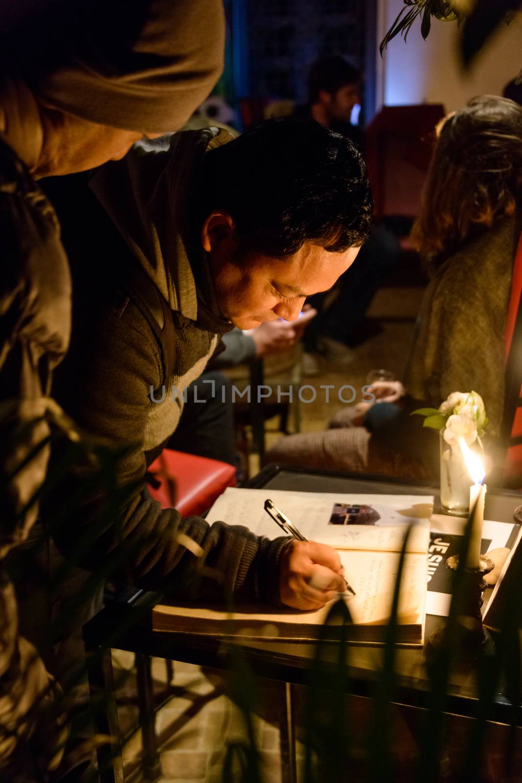 KATHMANDU, NEPAL - JANUARY 11, 2015: Man signing the condolences book at  the Cafe des Arts gathering in tribute to the victims of the terrorist attacks in Paris.