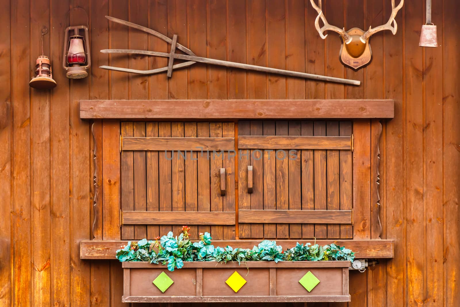 wood window on wood house and decorated with palnt,antler,lamp,bell and trident