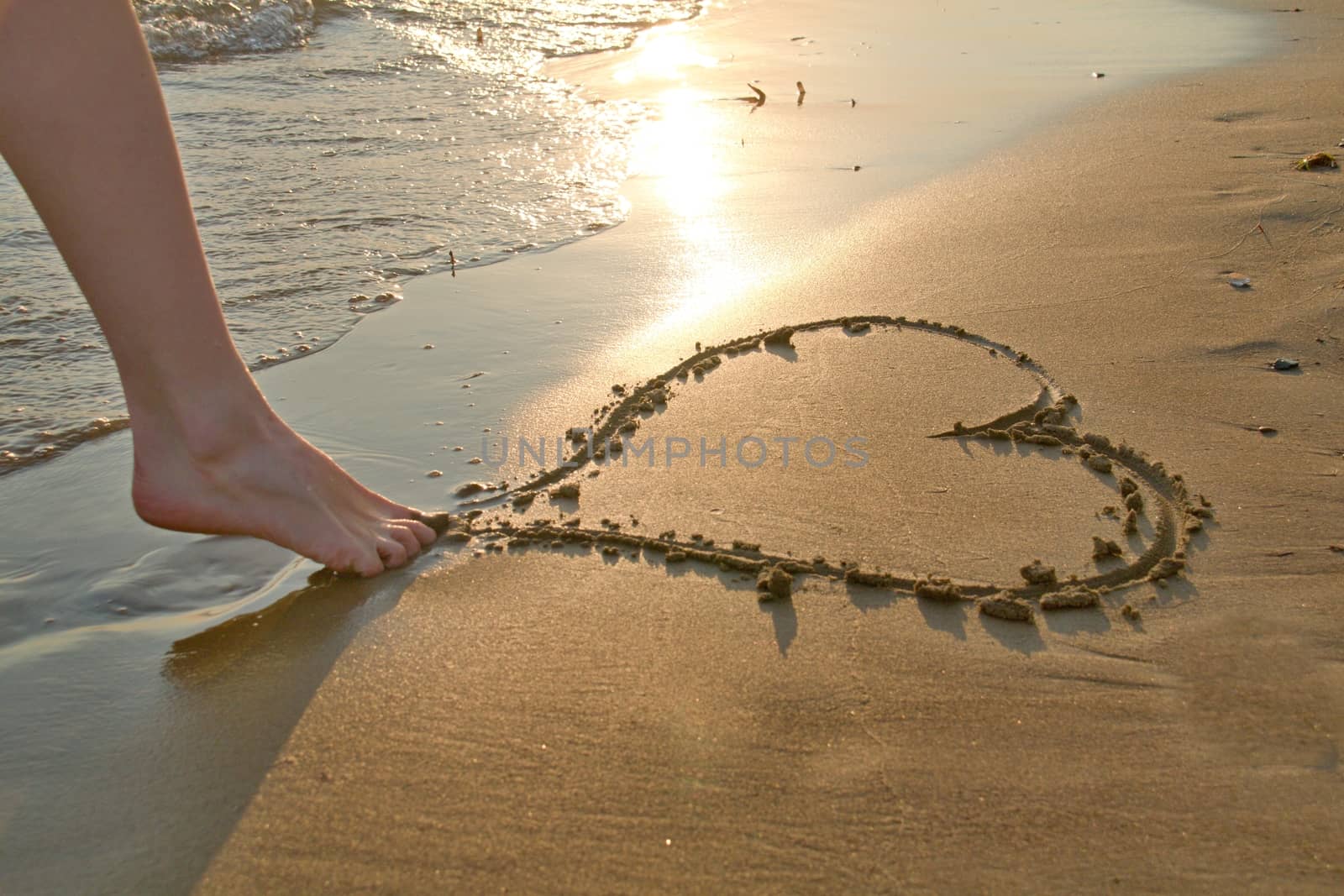 Photo shows a detail of the  heart written in the sand.