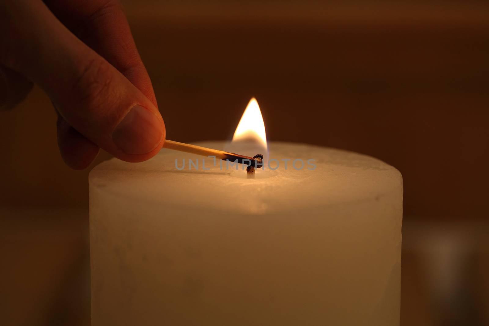 hand with a match lights a candle