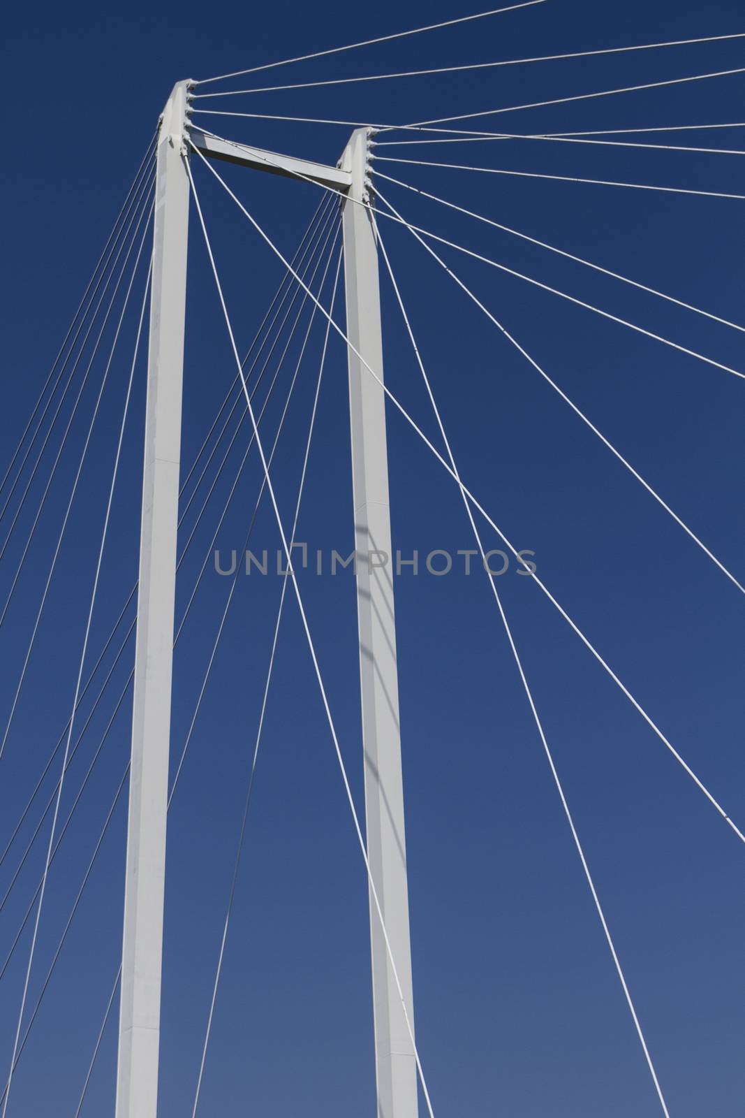 upper part of a suspension bridge with ropes and support before blue sky