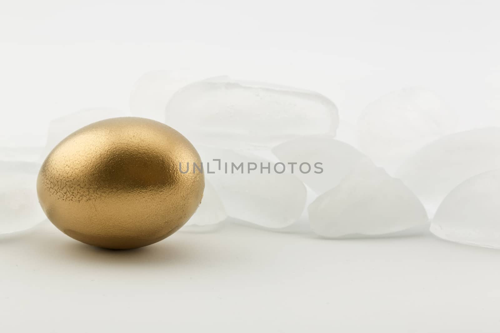 Wall of ice behind gold nest egg reflects risky conditions in economy, investment, and retirement. 